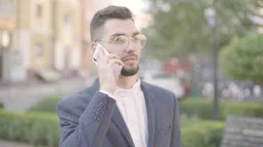 Yakışıklı kendine güvenen genç işadamı portresi ciddi akıllı telefon ile ortağı veya meslektaşı ile konuşan resmi bir takım elbise içinde. İş kavramı, serbest.