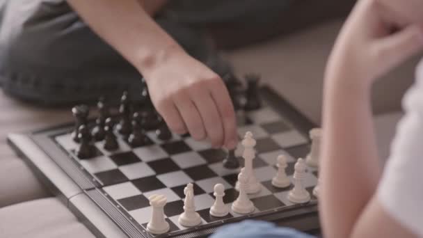 Close-up of two boys playing chess sitting on the couch. Siblings spending time at home. Happy family, carefree childhood. Intelligent game — Stock Video