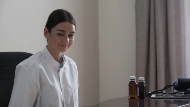 Retrato de una joven doctora profesional que ofrece verduras sentada en la oficina mirando a la cámara. Alimentos saludables en lugar de medicamentos y medicamentos. Concepto de profesión, medicina y — Vídeo de stock