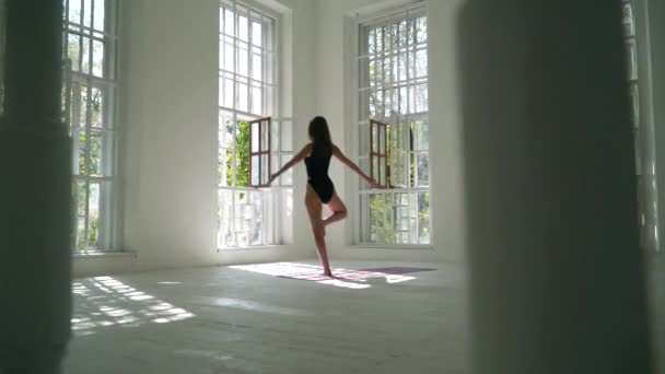 Genç kadın evde egzersiz yapmaktadır. Sağlıklı beyaz beyaz kız yoga pratik beyaz büyük odada paspas üzerinde duruyor. Genç kadın kapalı fitness egzersiz. Sağlıklı yaşam tarzı — Stok video