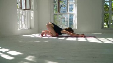 Sevimli genç kızıl saçlı sağlıklı beyaz kadın beyaz büyük odada paspas yoga. Spor giyim genç kadın kapalı fitness egzersiz.