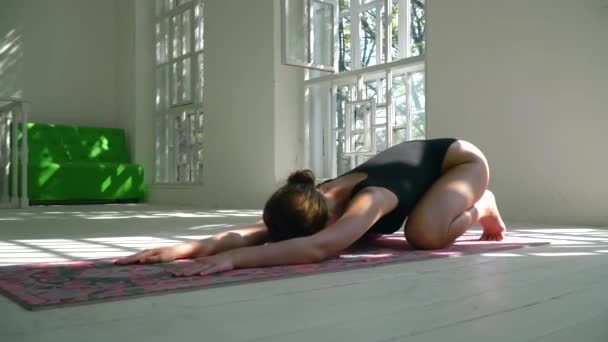 Skills young red-haired healthy caucasian woman practicing yoga on the mat in the white large room. Young woman in sports clothing exercising on fitness indoors. — Stock Video