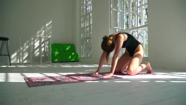 Junge rothaarige Fähigkeiten gesunde kaukasische Frau praktiziert Yoga auf der Matte im weißen großen Raum. junge Frau in Sportkleidung beim Fitnesstraining in Innenräumen. — Stockvideo