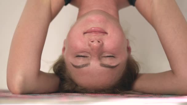 Портрет привлекательной концентрированной кавказки, практикующей йогу. Девушка, стоящая на голове в Ширшасане. Духовное развитие — стоковое видео