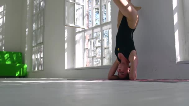 Belle femme caucasienne concentrée mince pratiquant le yoga. La fille debout sur sa tête près du mur. Développement spirituel — Video