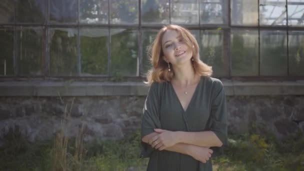 Portrait of confident cute young woman enjoying sun while standing at the old building. Concept of summertime, femininity, rest day — Stock Video