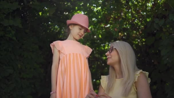 초상화 금발의 어머니와 그녀의 딸은 여름 정원이나 공원에서 카메라를보고 손가락으로 심장 모양을 형성합니다. 행복한 가족. 여자와 소녀 함께 옥외. — 비디오