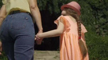 Anne ve kızı merdivenleri tırmanıyor. Sevimli sarışın anne yaz bahçesinde kızı ile yürüyüş veya parkta el ele tutuşarak. Mutlu bir aile. Kadın ve kız birlikte açık havada.