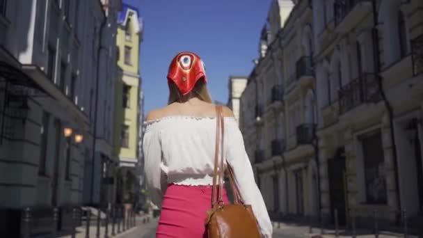 Mujer joven hermosa positiva caminando por la calle, girando y mirando a la cámara haciendo un gesto atractivo. Atractiva chica de moda disfrutando de un día soleado en la vieja ciudad europea — Vídeo de stock