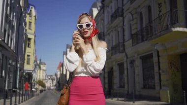 Sokakta duran güzel genç kadın cep telefonuyla konuşuyor. Eski Avrupa şehrinde güneşli bir gün zevk Çekici şık kız. Turizm konsepti