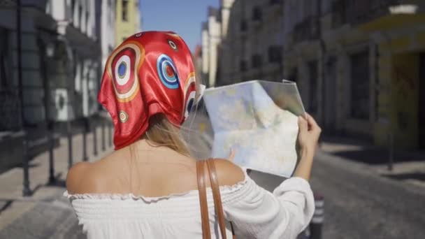 Πίσω θέα όμορφη νεαρή γυναίκα στέκεται στο δρόμο με το χάρτη στα χέρια. Ελκυστική μοντέρνα κορίτσι προσπαθεί να βρει έναν τρόπο στην παλιά Ευρωπαϊκή πόλη. Τουριστική έννοια, διακοπές — Αρχείο Βίντεο
