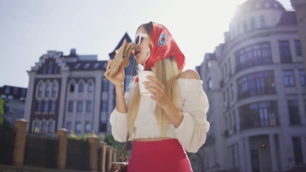 Porträt einer hübschen Frau, die auf der Straße Kaffee trinkt und Croissant isst. attraktive modische Mädchen genießen sonnigen Tag in der alten europäischen Stadt. Tourismuskonzept — Stockvideo