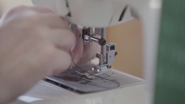 Close-up hand of seamstress inserts the thread into the needle of the sewing machine before starting work. Concept of job, profession, hobby — Stock Video
