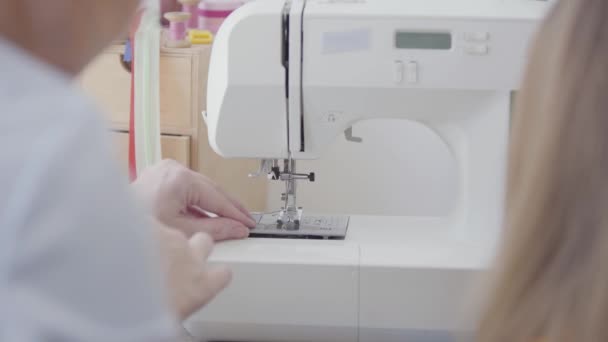 Close-up van naaister voegt de draad in de naald van de naaimachine voordat u begint met werken. De vrouw leert het meisje hoe te naaien. Begrip job, beroep, hobby — Stockvideo