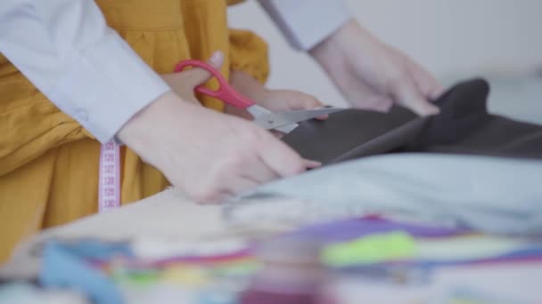 Close-up hands of a mother helping her daughter to cut a piece of beautiful fabric. Seamstress works at home. Happy loving family together — Stock Video