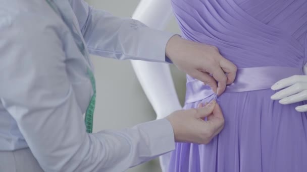 Femme corrige élégante robe violette qui pendent sur un mannequin dans la chambre. Travail de couturière à l'atelier. Coudre des vêtements. Créateur de mode . — Video