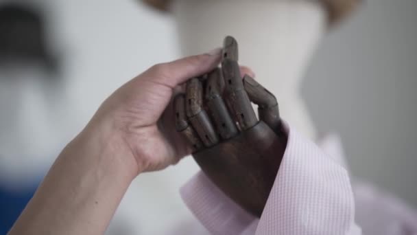 Женщина трогает искусственную руку и двигает пальцами манекена в шляпе и рубашке на заднем плане выставочного зала или магазина — стоковое видео