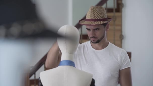 Ritratto bell'uomo barbuto che mette il cappello sulla testa del manichino. Il ragazzo che si diverte nello studio di cucito — Video Stock