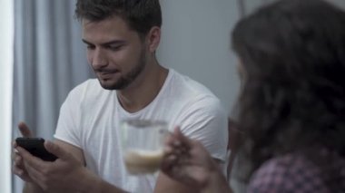 Akıllı telefon ve kıvırcık kız tatilde stüdyoda rahatlatıcı latte içme mesaj yazarak genç hipster adam Portresi