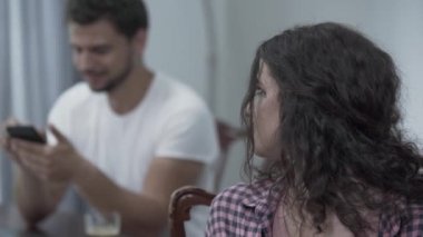 Üzgün ağlayan kadın ön planda dönüyor ve başka bir kadınla sohbet ederken gülümseyen sadakatsiz kocasına bakıyor. Hile kavramı, kırık aile