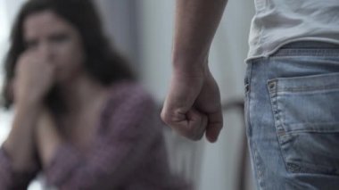 Korkmuş karısının önünde yumruğunu sıkan kızgın bir adamın yakın çekim. Ailede şiddet. Mutsuz bir ilişki. Fiziksel taciz kurbanı. Ön plana odaklanın.