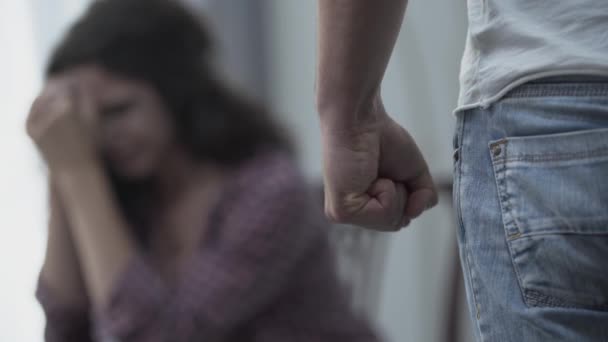 怖い妻の前に立って拳を握りしめた怒った男のクローズアップ。家族の暴力不幸な関係身体的虐待の被害者背景に焦点を当てる. — ストック動画
