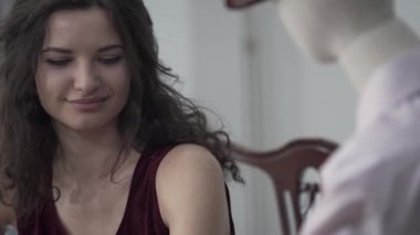 Çekici kıvırcık kadın gerçek erkek ile tarih taklit şapka bir erkek manken ile kırmızı şarap içme masada oturan. Hayal konsepti, hayal gücü, yalnızlık. Kamera aşağı hareket ediyor