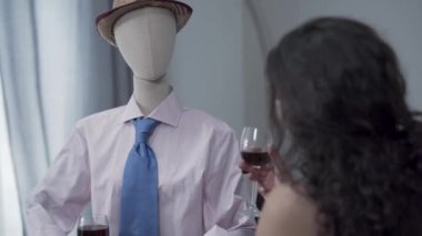 Sevimli kıvırcık kadın gerçek erkek ile tarih taklit şapka bir erkek manken ile kırmızı şarap içme masada oturuyor. Rüya kavramı, hayal gücü, yalnızlık