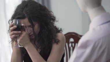 Sevimli ağlayan kıvırcık kadın gerçek erkek ile tarih taklit bir erkek manken ile kırmızı şarap içme masada oturan. Rüya kavramı, hayal gücü, yalnızlık