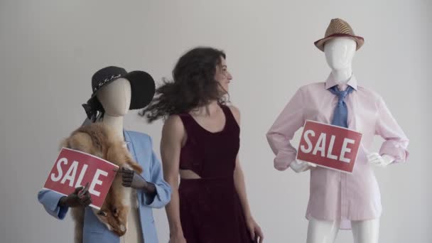 Gelukkige vrouw in de buurt van de moderne mannequins in elegante kleren met de rode borden zeggen verkoop. Emotionele dame kijken naar camera. — Stockvideo