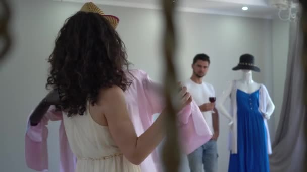 Young woman having fun dancing slow dance with mannequin dressed in extravagant hat and fur coat on the background of showroom or shop — Stock Video