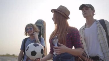Genç arkadaşlar grubu dinlenmek ve eğlenmek için yaz akşamı gitar ve futbol topu ile plaja geldi