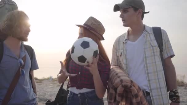 Група друзів приїхала на пляж з гітарою і футбольним м'ячем в літній вечір, щоб розслабитися і розважитися — стокове відео