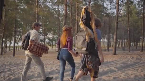 Tři z mladých přátel hipíků přišli na pláž s kytarou a fotbalovou koulí v létě večer, aby si odpočini a bavili — Stock video