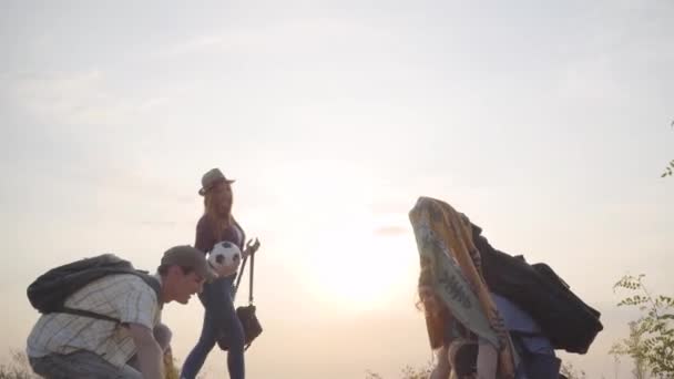 Groep jonge vrienden kwam naar het strand met gitaar en voetbal bal op de zomeravond om te ontspannen, plezier te hebben en te picknicken — Stockvideo