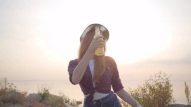 Genç hipster kız portre akşam deniz plajı arka planda bira veya limonade soğuk şişe kusma.