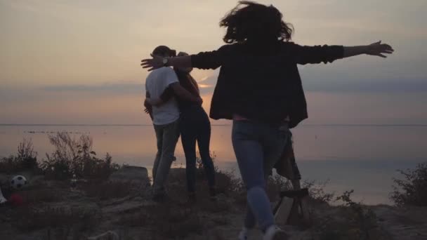 La jeune fille a couru vers des amis debout sur les rives d'une rivière ou d'un lac et câlins avec chacun . — Video