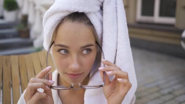 Portrétní mladá žena v brýlích a s ručníkem na hlavě venku. Sebevědomá dívka si užívá krásného jitra venku. Externí. — Stock video