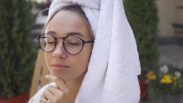 Portrait de jeune femme adorable dans des lunettes et avec une serviette sur la tête à l'extérieur. Fille confiante profiter d'une belle matinée en plein air. Freelance . — Video