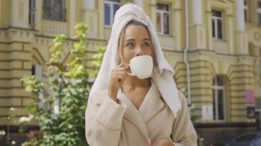 Sokakta kahve içen başında havlu ile bornoz lu gülümseyen genç kadın portresi. Kendine güvenen kız şehirde güzel bir gün zevk. Serbest kavram