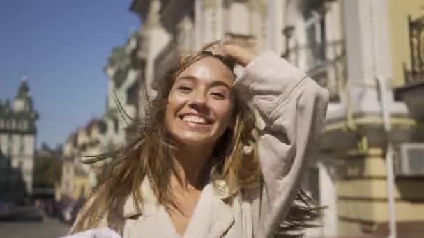 Alegria jovem confiante feliz andando pela rua. A menina olhando para a câmera e e sopra um beijo . — Vídeo de Stock