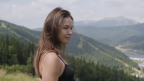 Linda mujer de moda de pie frente a un hermoso paisaje, su pelo revoloteando. Conexión con la naturaleza salvaje. Ocio al aire libre, estilo de vida activo. Turismo, viajes — Vídeo de stock