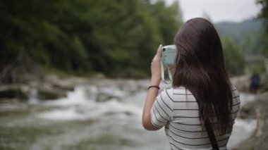 Kız bir dağ nehrinin fotoğrafını yapıyor. Turiska dağlarda dinlenmenin keyfini çıkarır. Seyahat, tatil.