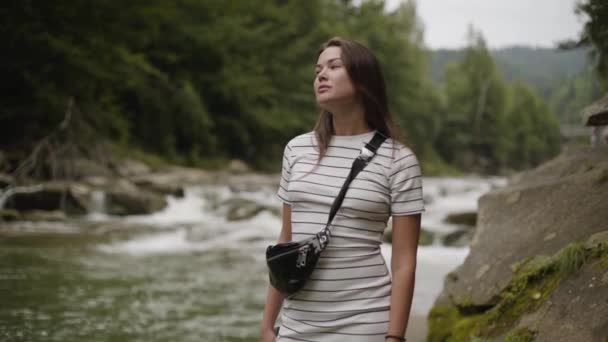 Hermosa mujer mirando hacia otro lado parada en la orilla del río en el bosque. La chica caminando en el bosque. Conexión con la naturaleza. Viajar, vacaciones — Vídeos de Stock