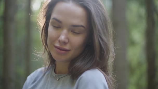 Porträtt av söt kvinna som tittar bort stående i solljus i den gröna skogen. Flickan som vandrar i skogen. Koppling till naturen. Resor, semester — Stockvideo