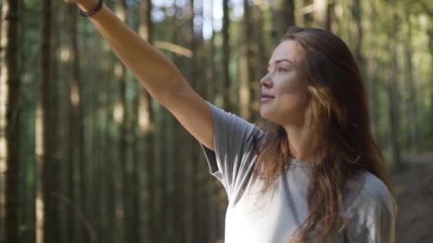 Yeşil ormanda güneş ışığından yüzünü koruyan güzel bir kadının portresi. Ormanda yürüyüş eden kız. Doğayla bağlantı. Seyahat, tatil. Yavaş çekim — Stok video