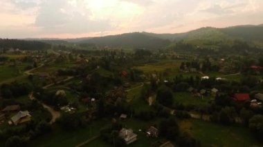 Aerial view of small modern tourist village hiding among mountains. Connection with nature. Traveling, tourism, vacation. Sunny day. Drone shooting, top view