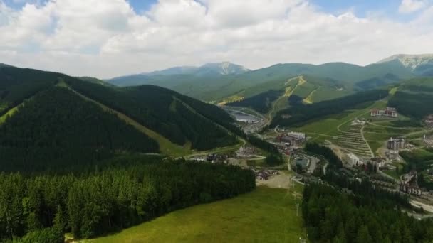 Frumos peisaj montan. Un mic oraș turistic care se ascunde printre păduri și munți. Legătura cu natura. Călătorii, turism, vacanţă. O zi însorită. Tragere cu drone — Videoclip de stoc