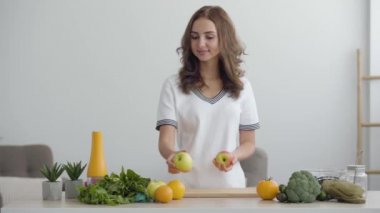 Genç beceri kadın modern mutfakta dururken masaya elma koyar. Sağlıklı gıda kavramı. Nutri terapisti, nutraceutical, beslenme uzmanı, sağlıklı yaşam koçu mesleği.