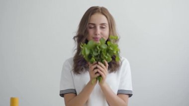 Genç güzel kadın modern mutfakta masada duran taze yeşillik koklama. Sağlıklı gıda kavramı. Nutri terapisti, nutraceutical, beslenme uzmanı, sağlıklı yaşam koçu mesleği